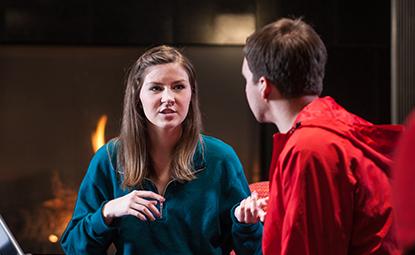 Two people sitting in front of a fireplace talking