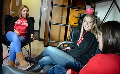 Three women sitting in a residential hall room talking